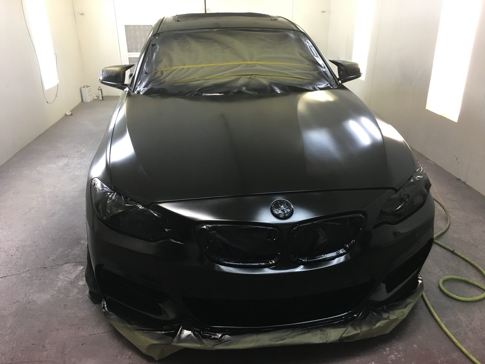 Black BMW being refinished inside the J&J Automotive Repair paint booth